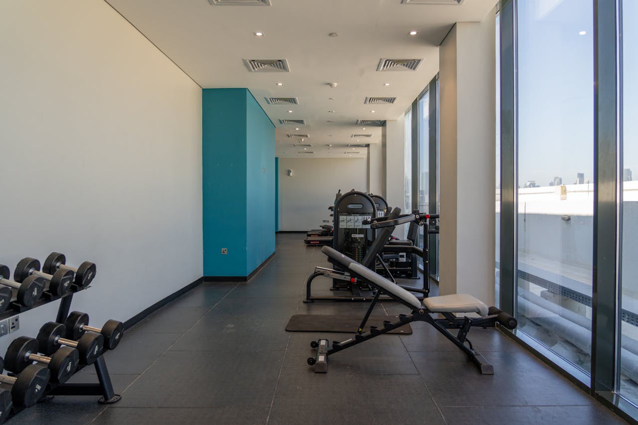 Spacious gym with exercise machines and dumbbells, perfect for bodybuilding and fitness enthusiasts.